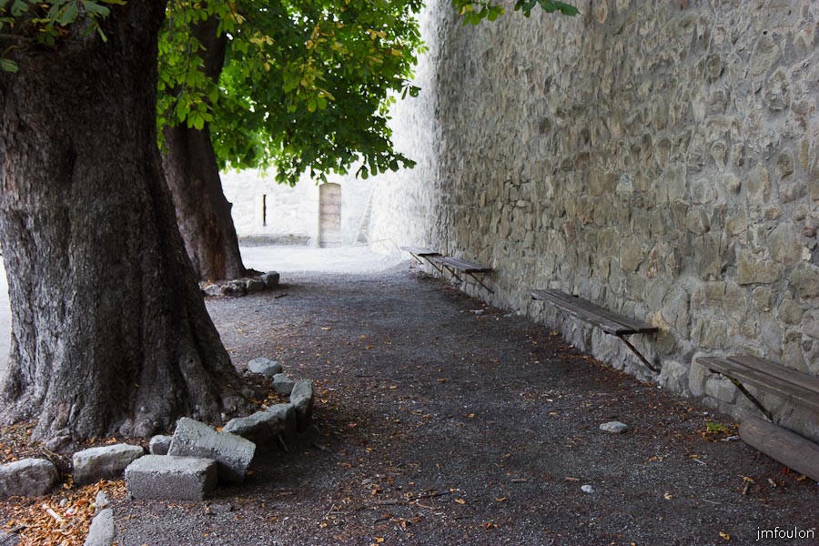 colmars-007.jpg - Colmars-les-Alpes - Bancs et arbres séculaires au pied des fortifications entre la Tour Garcin et la Porte de France.