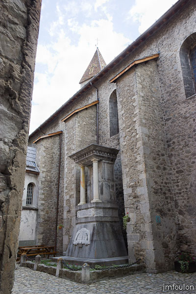colmars-027.jpg - Colmars-les-Alpes - Place Saint Jean - Le monuments aux Morts et l'imposante maçonnerie de l'église Saint Martin (XVIIe).