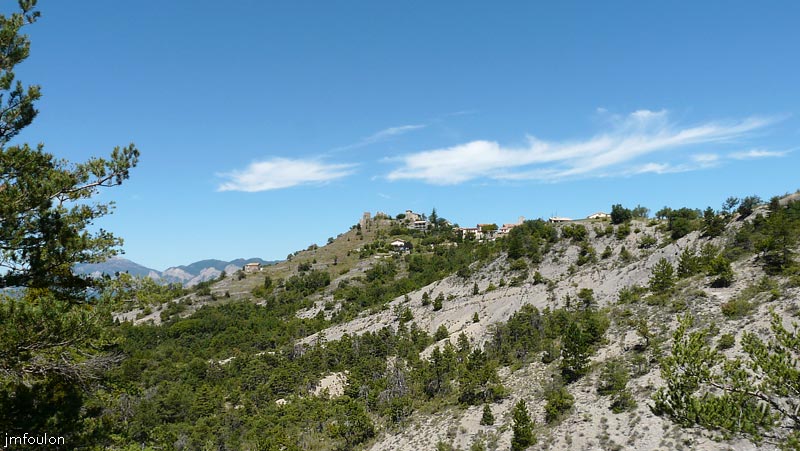 chateau-sigoyer-02web.jpg - Le Château au sommet de sa butte et le village à sa droite vus depuis la route de Thèze