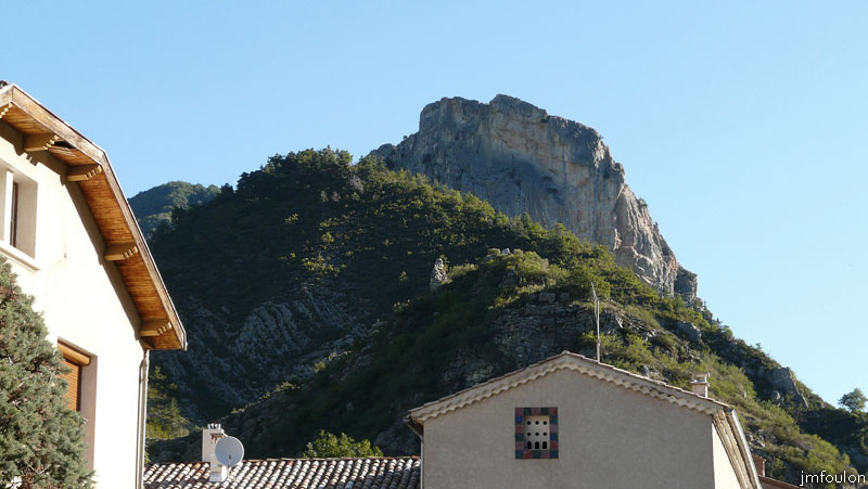 tour-le-caire-01web.jpg - La Tour sur sa butte au second plan, vue de la D 951 qui longe le village et le torrent du Grand Vallon. En arrière plan, la montagne de Piefourcha (1437 m)