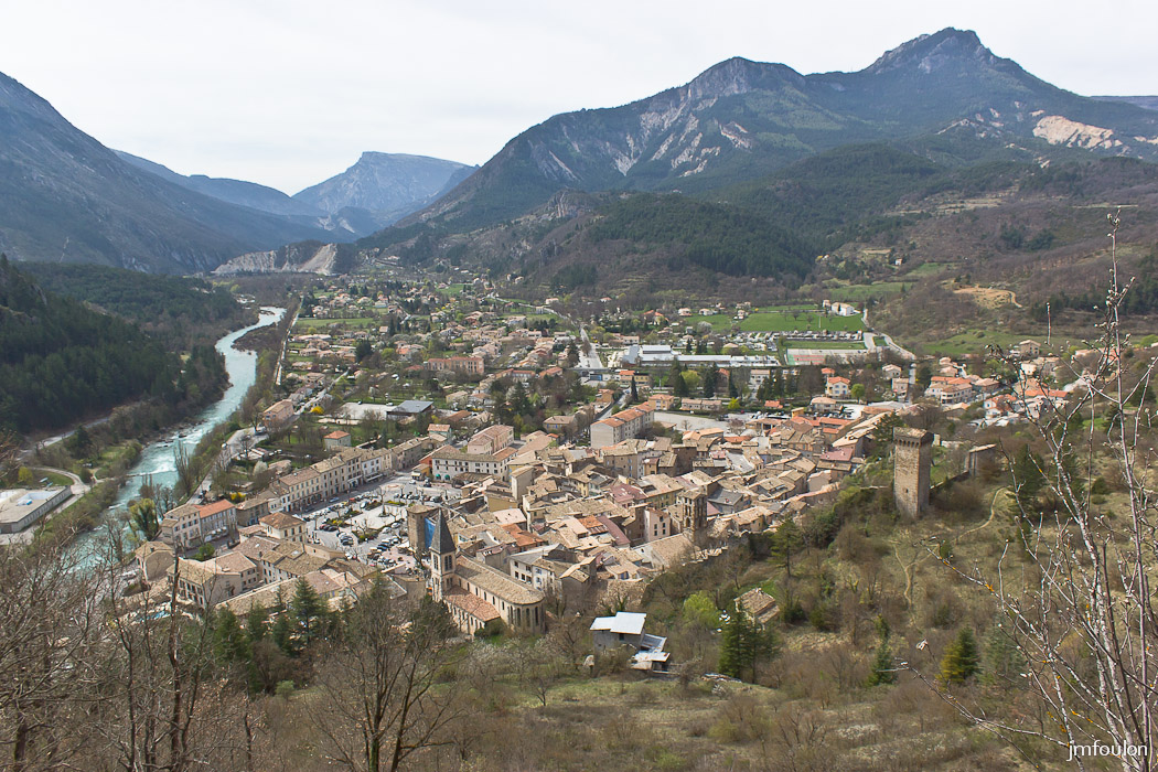 castellane-055.jpg - Vue sur Castellane depuis le chemin empierré qui monte à Notre Dame du Roc. On voit bien à droite les vestiges des remparts et la Tour Pentagonale. A gauche coule le Verdon