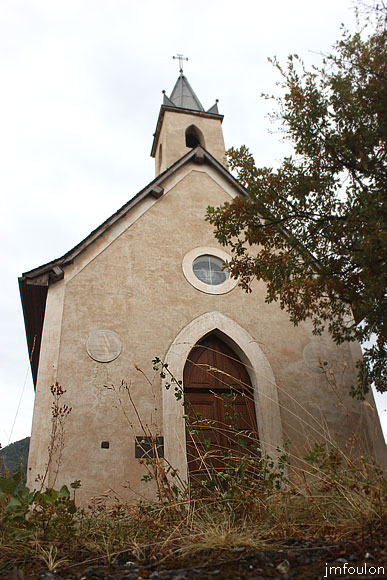 remollon--st-roch-03web.jpg - Remollon - Chapelle Notre Dame de Clémence dite Saint Roch -L'entrée surmontée d'un petit oculus. A gauche un médaillon en mémoire de la Vierge
